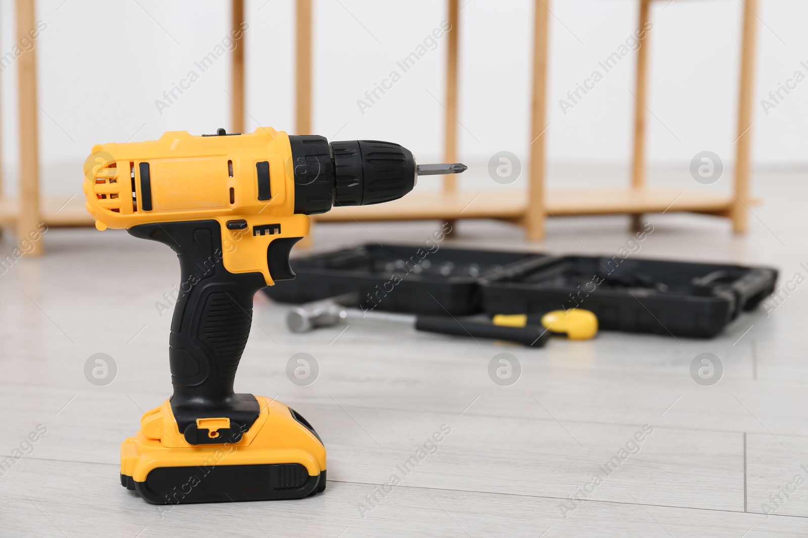 Photo of Cordless electric screwdriver and other tools on floor in room