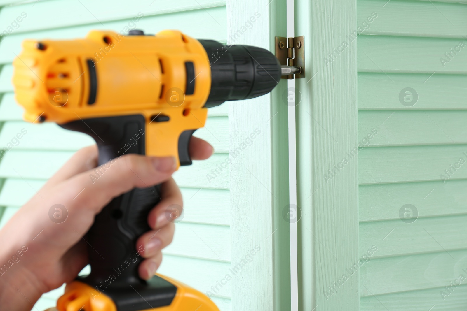 Photo of Woman with electric screwdriver assembling folding screen at home, closeup