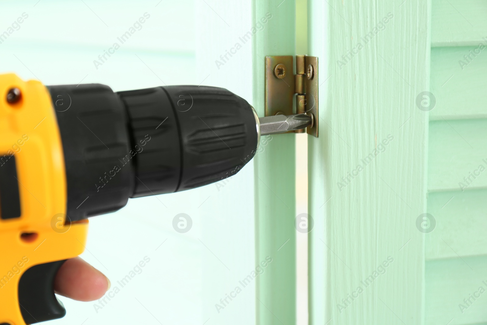 Photo of Woman with electric screwdriver assembling folding screen at home, closeup