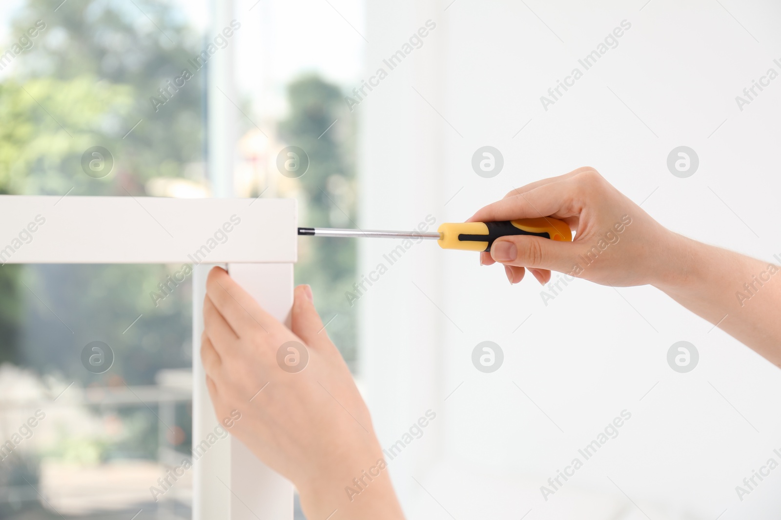 Photo of Woman with screwdriver assembling furniture indoors, closeup