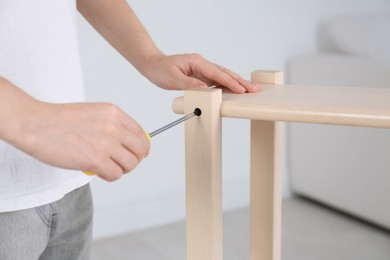 Photo of Woman with screwdriver assembling furniture indoors, closeup