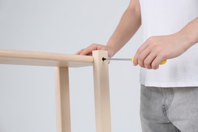 Photo of Woman with screwdriver assembling furniture indoors, closeup