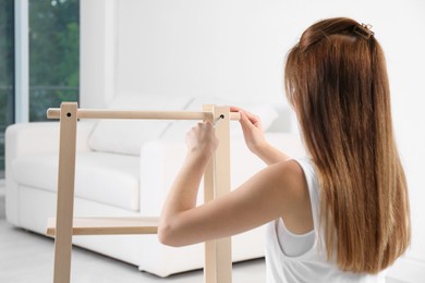 Photo of Woman with screwdriver assembling furniture at home