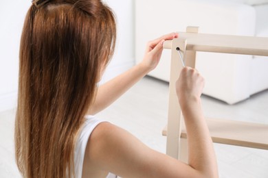 Woman with screwdriver assembling furniture at home