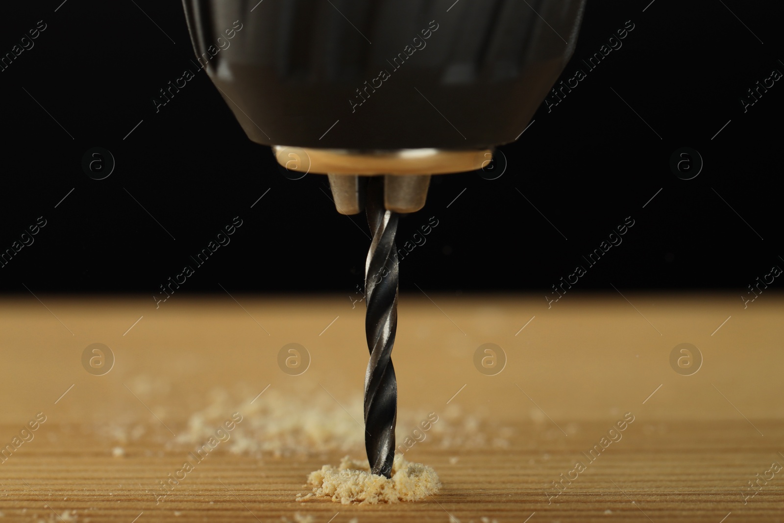 Photo of Drilling hole in wooden plank on black background, closeup