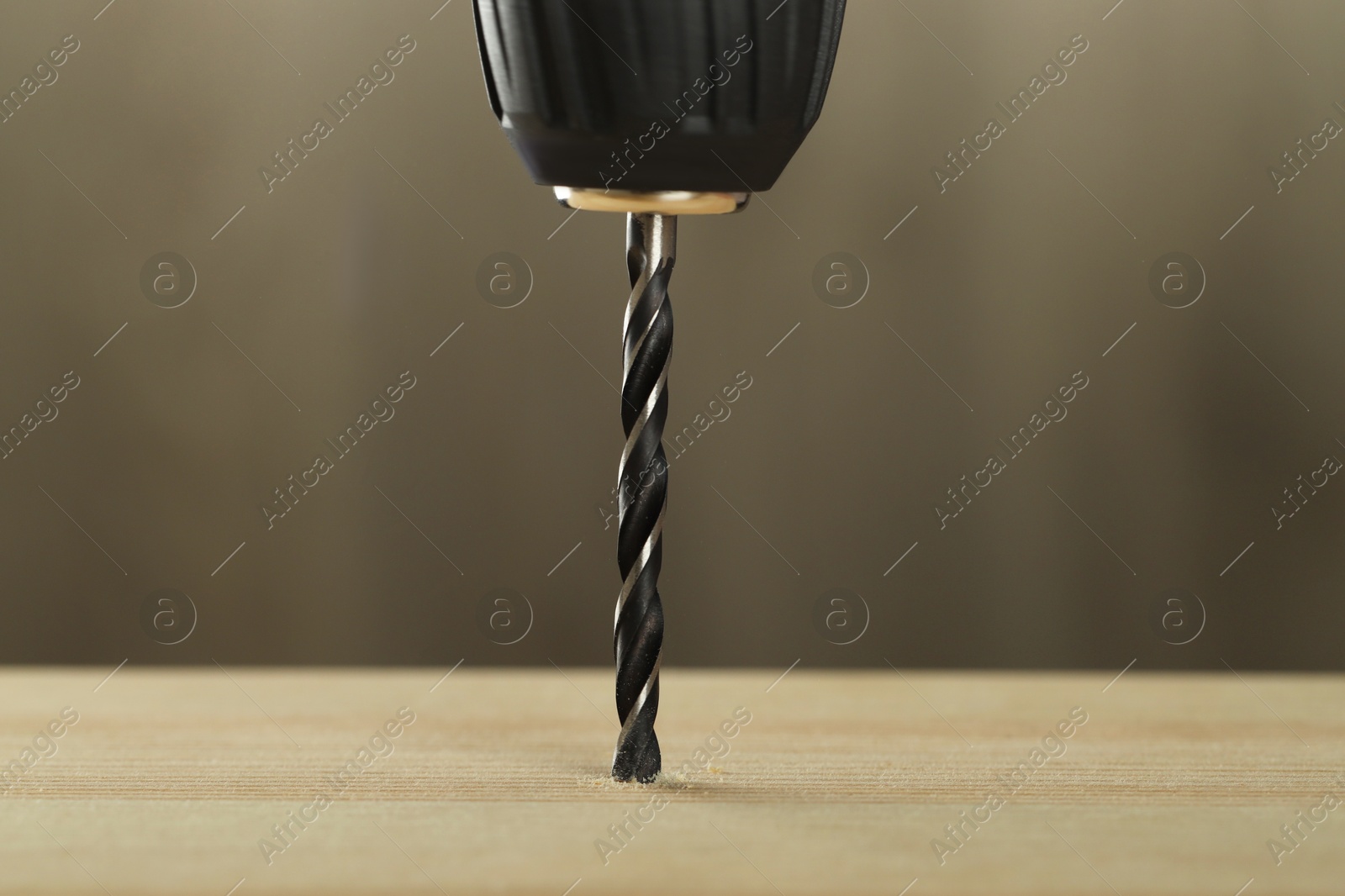 Photo of Drilling hole in wooden plank on grey background, closeup