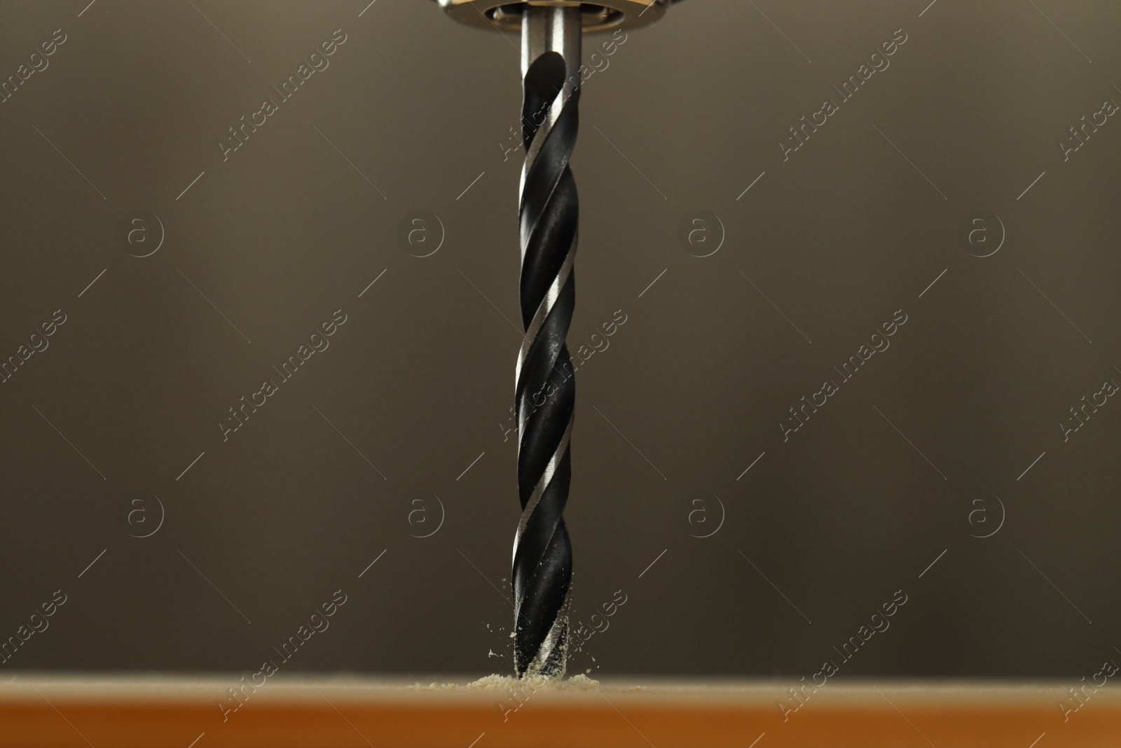 Photo of Drilling hole in wooden plank on grey background, closeup