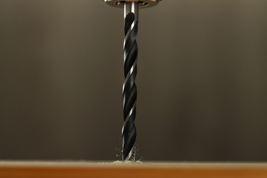 Photo of Drilling hole in wooden plank on grey background, closeup