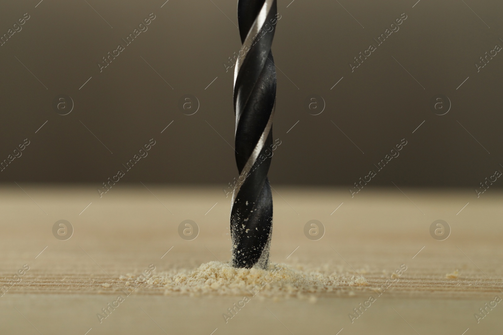 Photo of Drilling hole in wooden plank on grey background, closeup