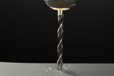 Photo of Drilling hole in grey surface on black background, closeup