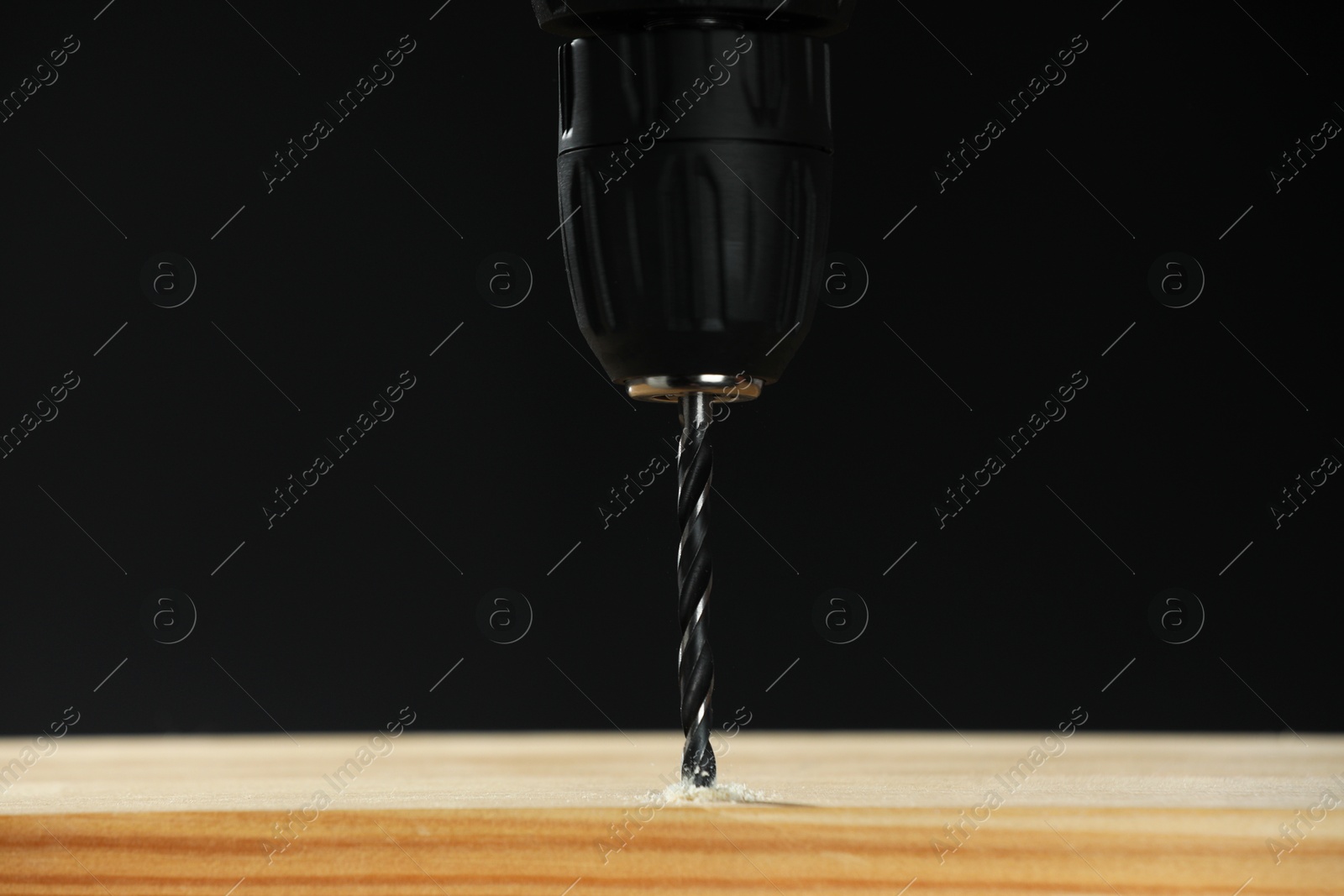 Photo of Drilling hole in wooden plank on black background, closeup