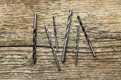 Photo of Many drill bits on wooden table, flat lay