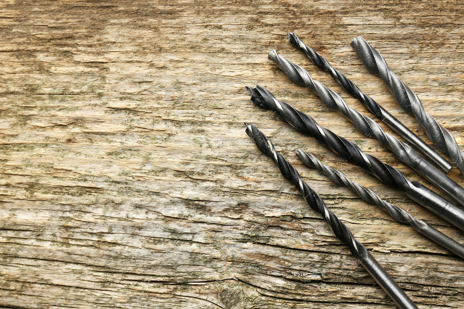 Photo of Many drill bits on wooden table, flat lay. Space for text