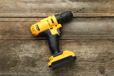 Photo of Cordless electric drill on wooden table, top view