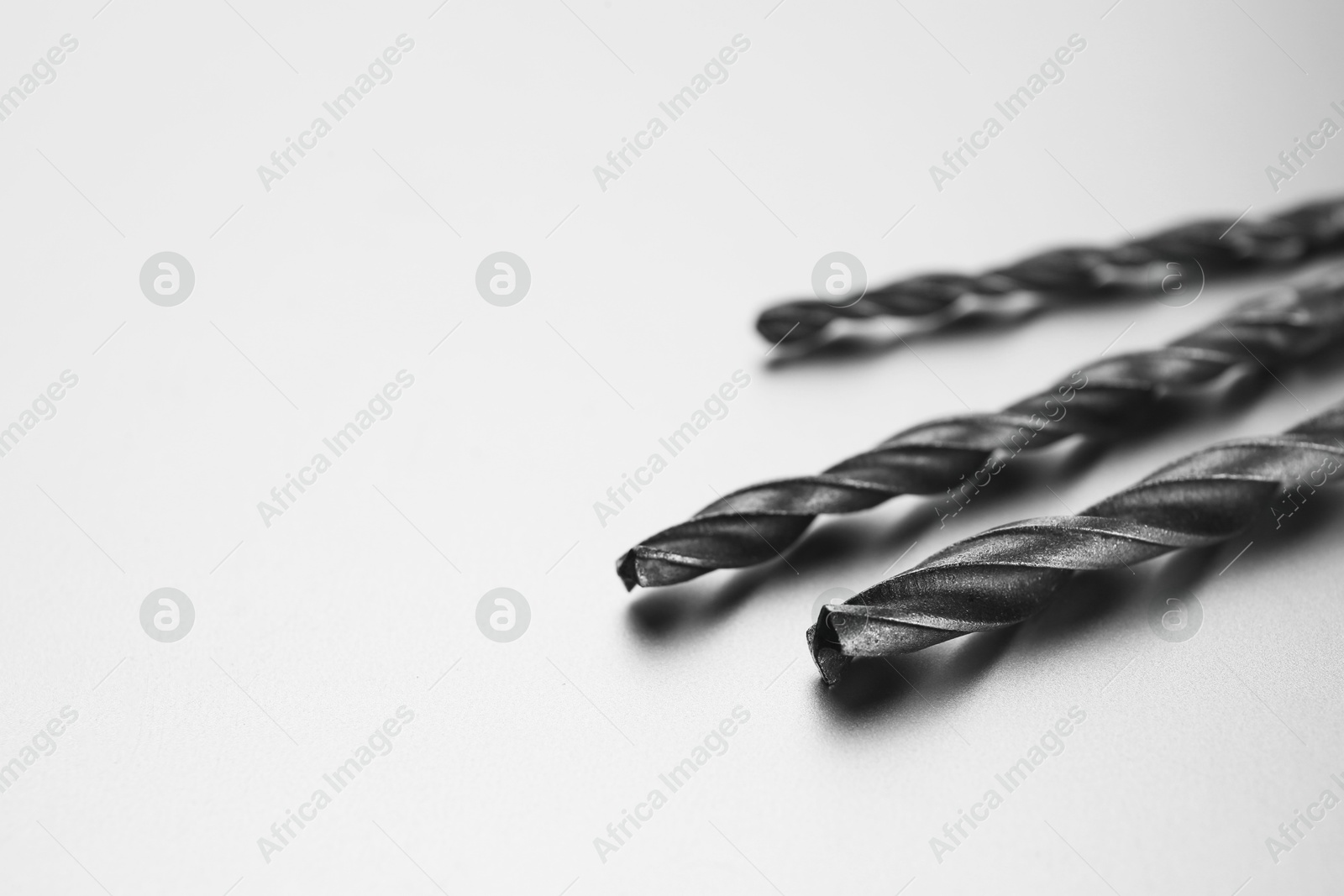 Photo of Different drill bits on light grey background, space for text