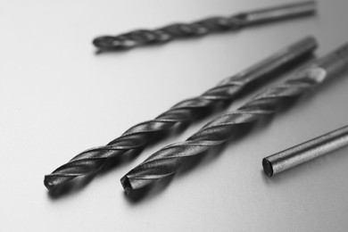 Many different drill bits on light grey background, closeup