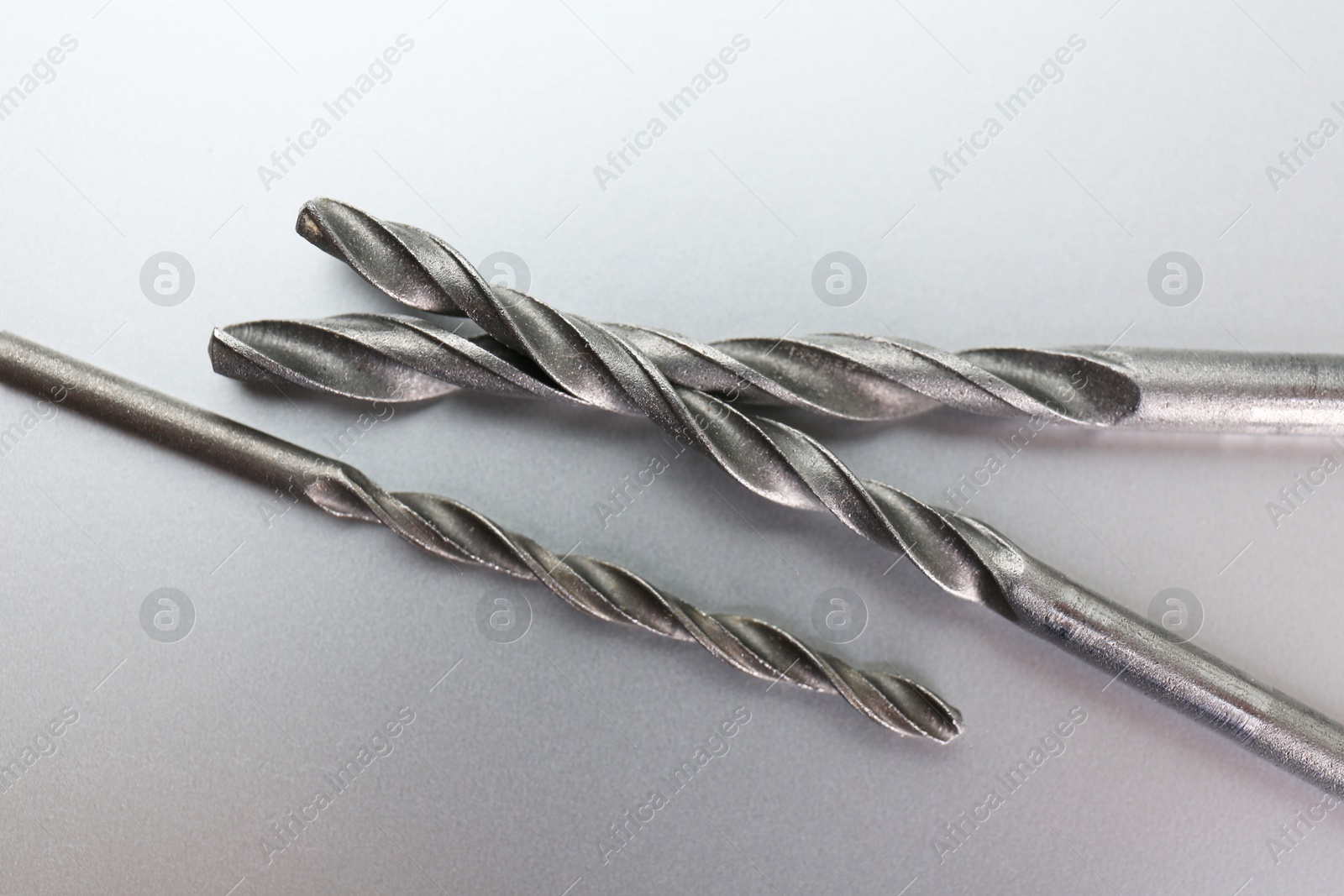 Photo of Different drill bits on light grey background, above view