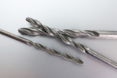 Different drill bits on light grey background, above view