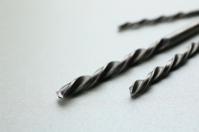 Photo of Different drill bits on light grey background, closeup