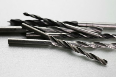 Photo of Many different drill bits on light grey background, closeup