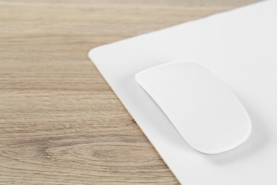 Photo of White computer mouse and mousepad on wooden table