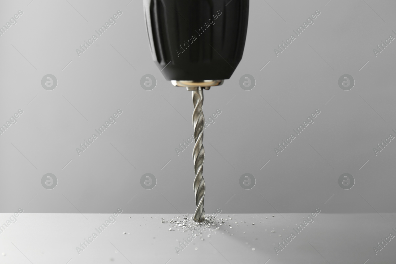 Photo of Drilling hole in light surface on gray background, closeup