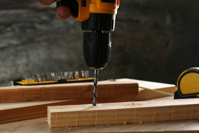 Drilling hole in plank on wooden table, closeup