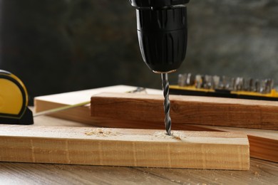 Photo of Drilling hole in plank on wooden table, closeup