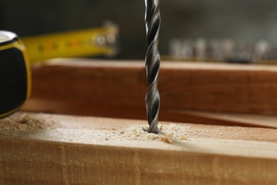 Drilling hole in wooden plank on table, closeup