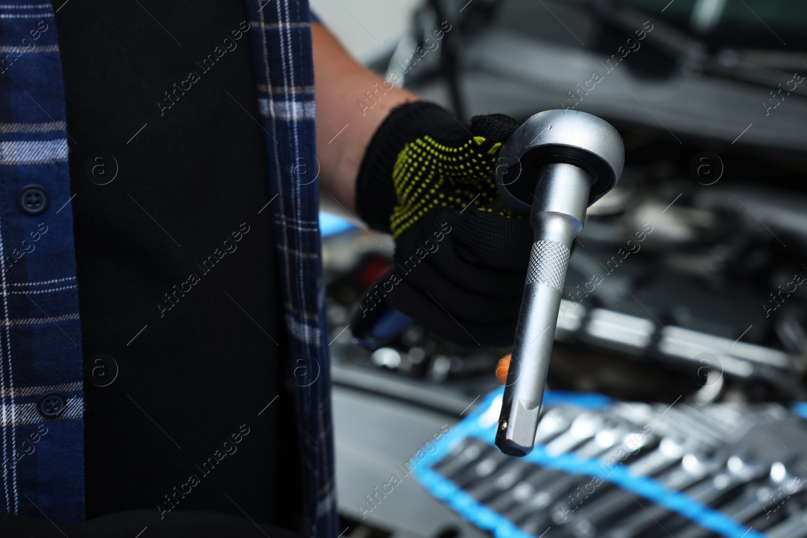 Photo of Auto mechanic with torque wrench at automobile repair shop, closeup