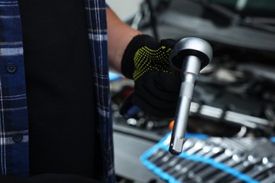 Photo of Auto mechanic with torque wrench at automobile repair shop, closeup