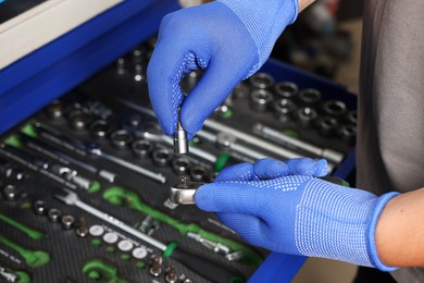 Auto mechanic with different tools at automobile repair shop, closeup