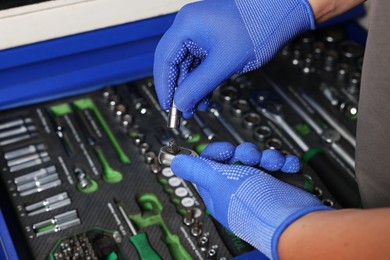 Auto mechanic with different tools at automobile repair shop, closeup