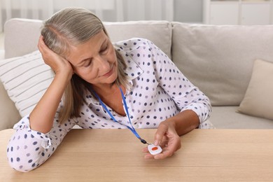 Senior woman pressing emergency call button at home