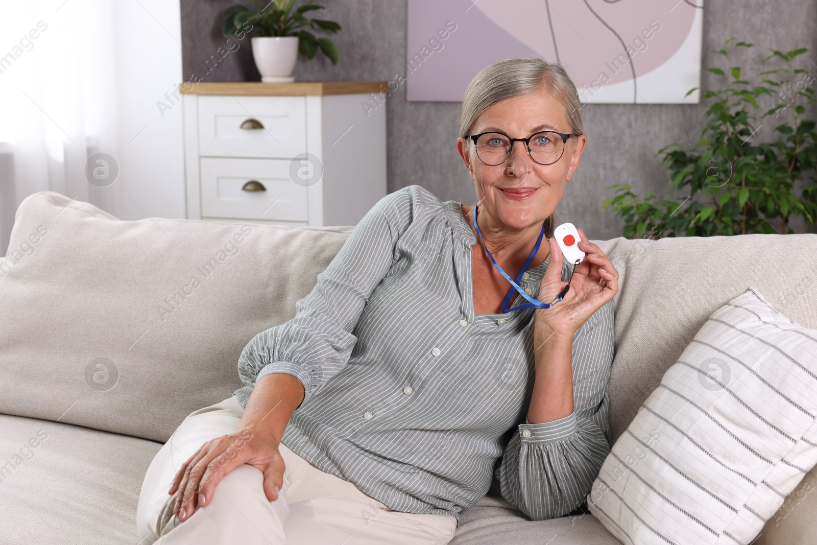 Photo of Happy senior woman with emergency call button at home