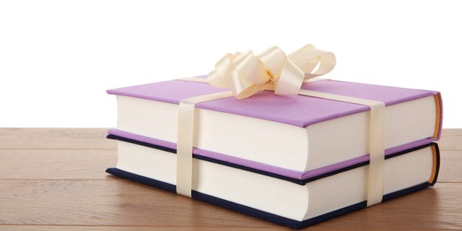 Photo of Hardcover books with ribbon as gift on wooden table against white background