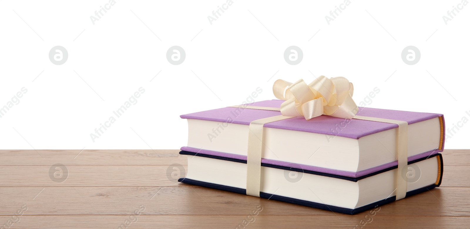 Photo of Hardcover books with ribbon as gift on wooden table against white background