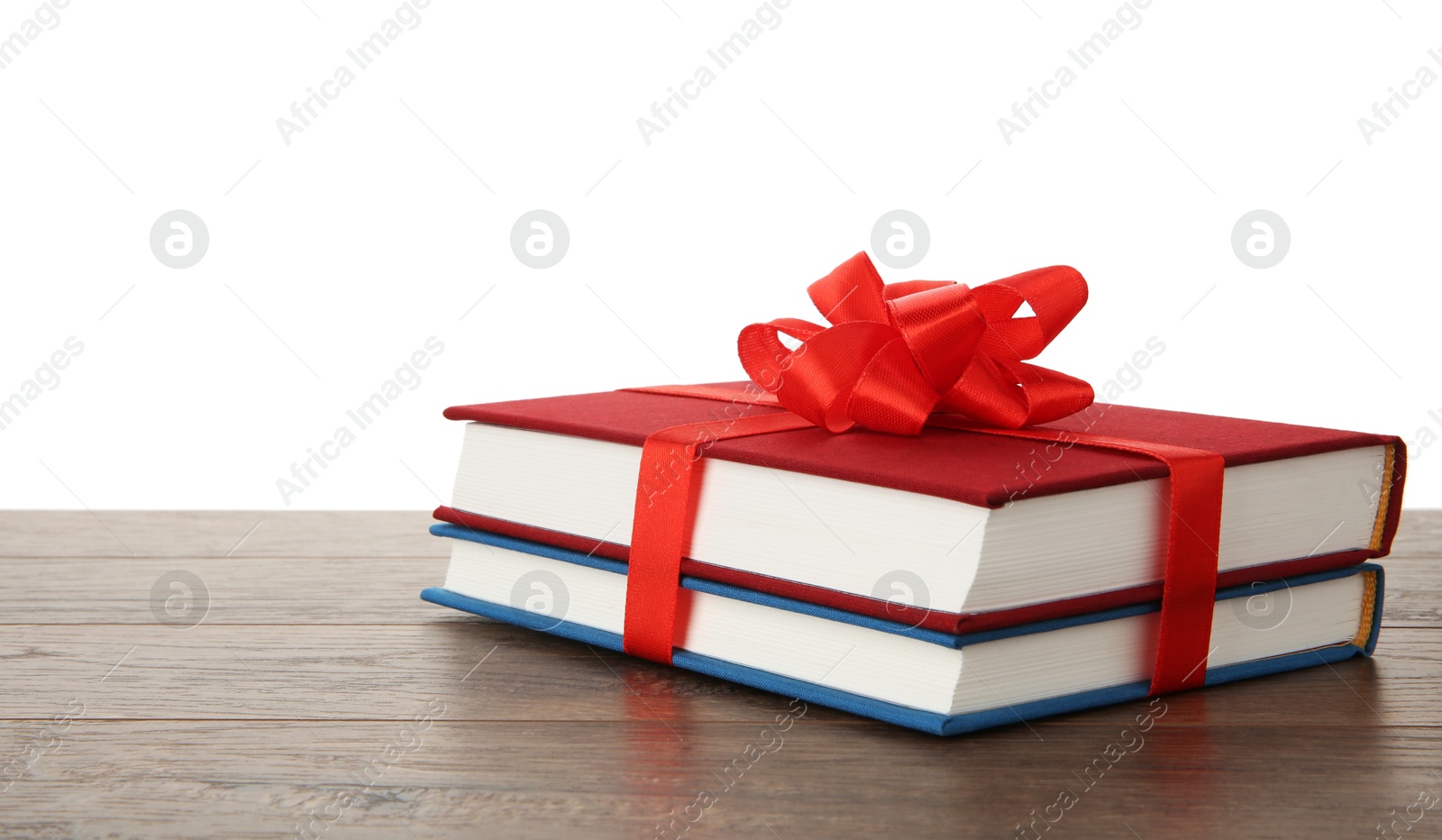 Photo of Hardcover books with ribbon as gift on wooden table against white background