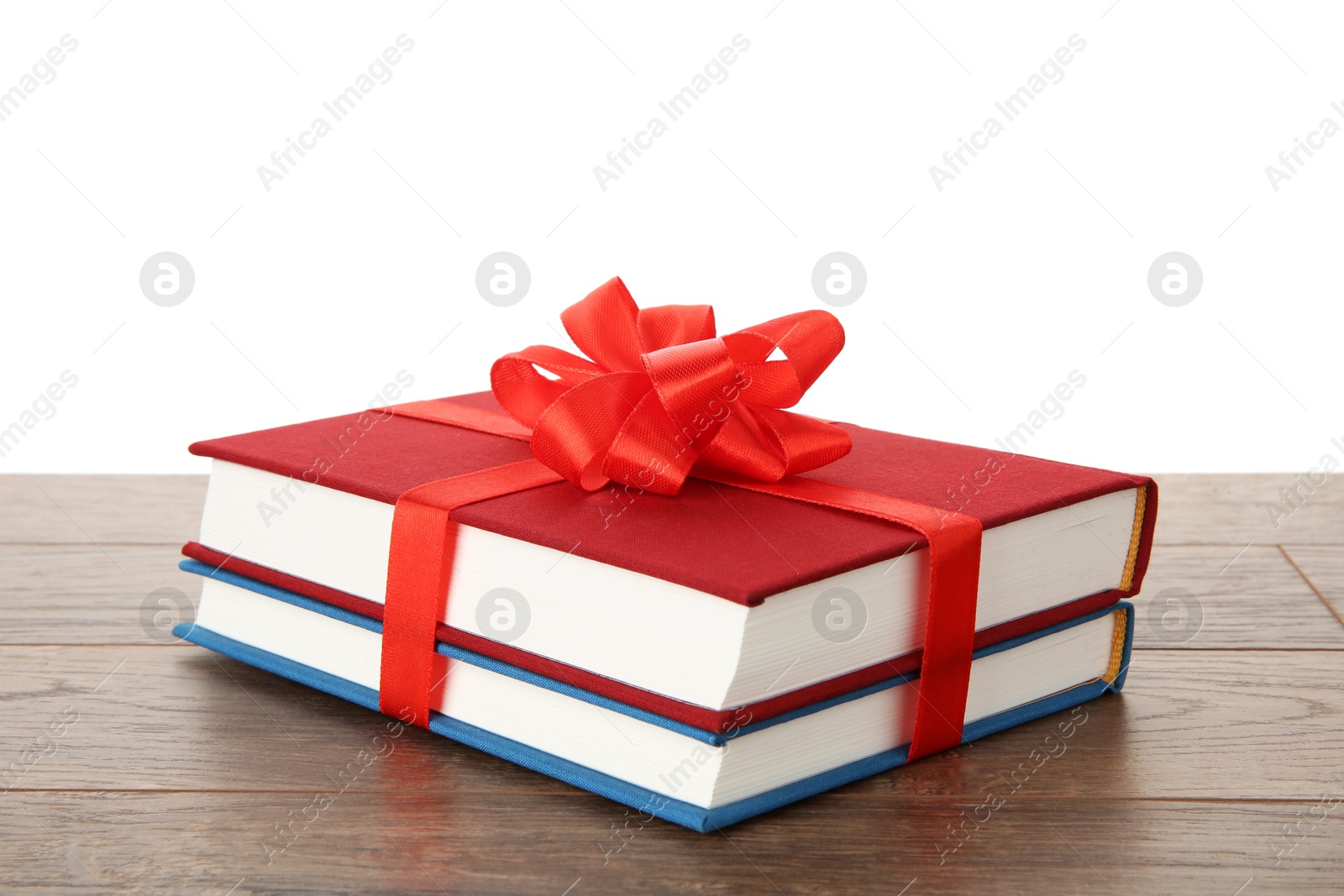 Photo of Hardcover books with ribbon as gift on wooden table against white background