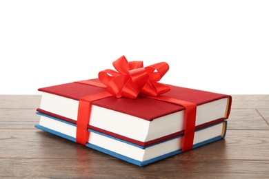 Photo of Hardcover books with ribbon as gift on wooden table against white background