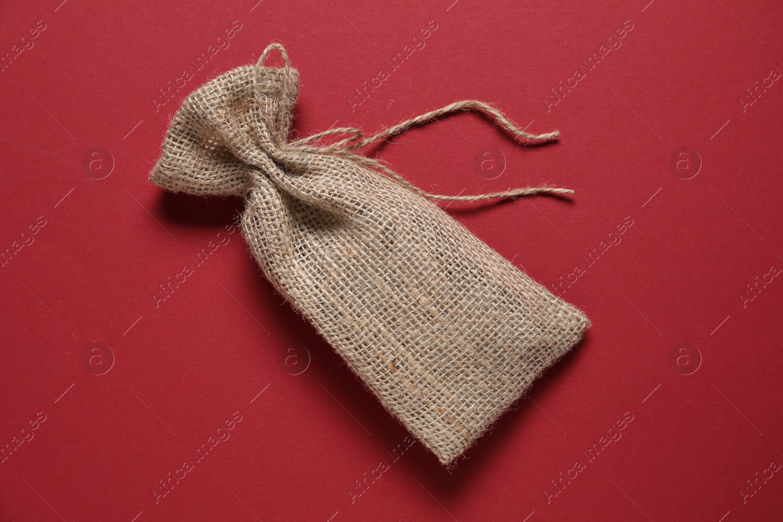 Photo of One burlap sack on red background, top view