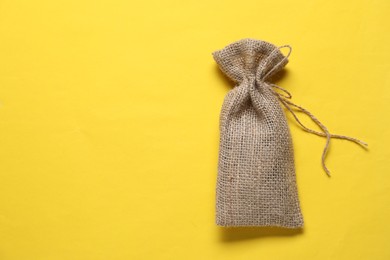 One burlap sack on yellow background, top view. Space for text