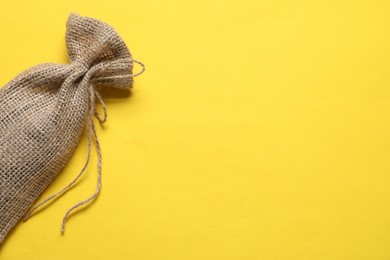 One burlap sack on yellow background, top view. Space for text