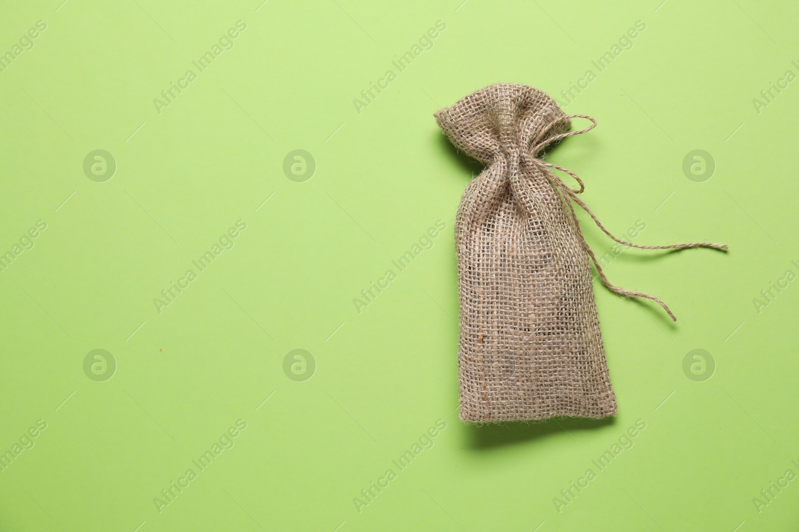 Photo of One burlap sack on light green background, top view. Space for text