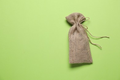 Photo of One burlap sack on light green background, top view. Space for text