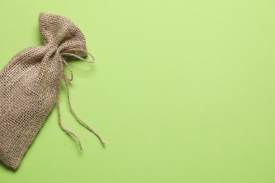 Photo of One burlap sack on light green background, top view. Space for text