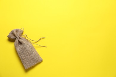 One burlap sack on yellow background, top view. Space for text