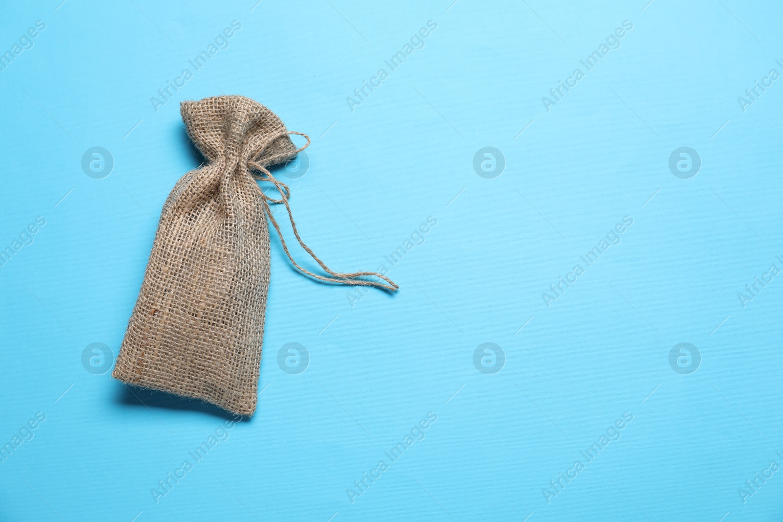 Photo of One burlap sack on light blue background, top view. Space for text