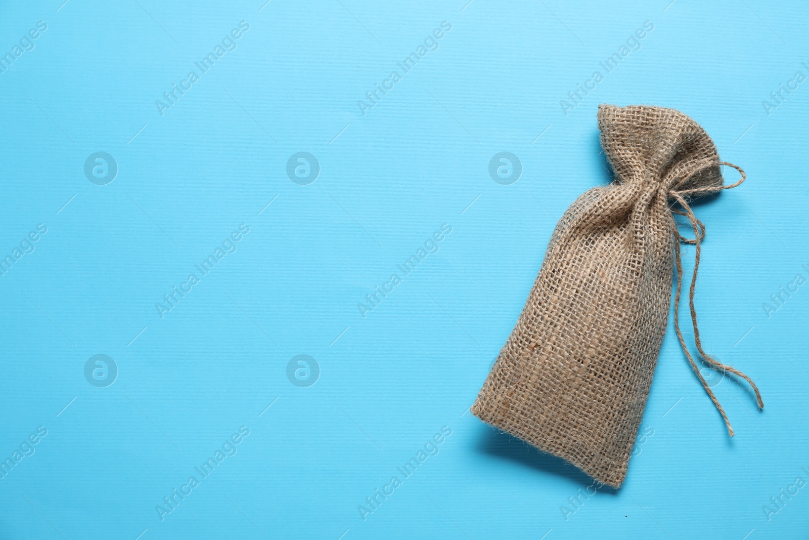 Photo of One burlap sack on light blue background, top view. Space for text