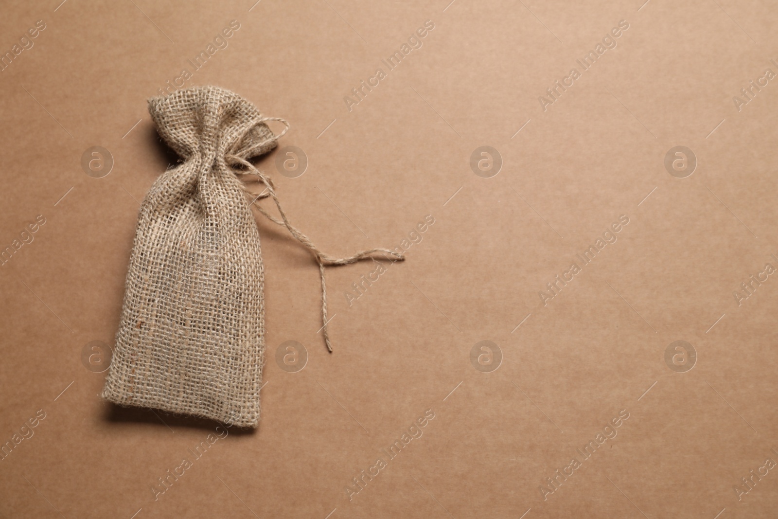 Photo of One burlap sack on brown background, top view. Space for text